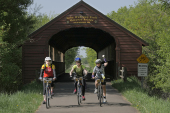 Cyclist under scenic bridge Minnesota Lake Wobegon Trail Bike Tour