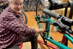 Photo shows woman repairing a bicycle. 