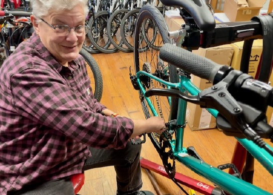 Photo shows woman repairing a bicycle. 