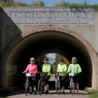 Four WomanTours cyclists celebrate their climb to the Great Continental Divide on the Great Allegheny Passage.