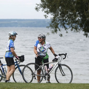 Cyclist resting by lake shore Finger Lakes Bike Tour