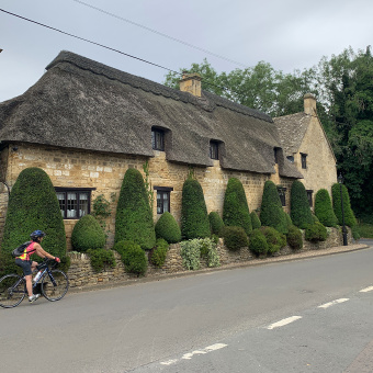 Cotswolds single cyclist by house