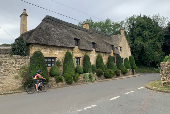 Cotswolds single cyclist by house